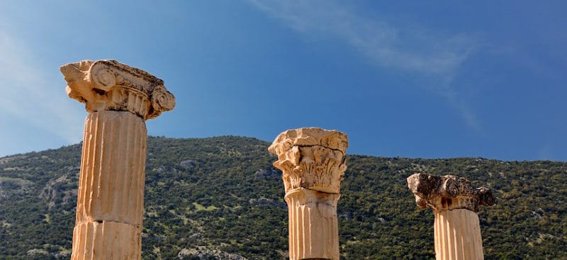 Three ancient column capitals at Ephesus rising against a deep blue sky