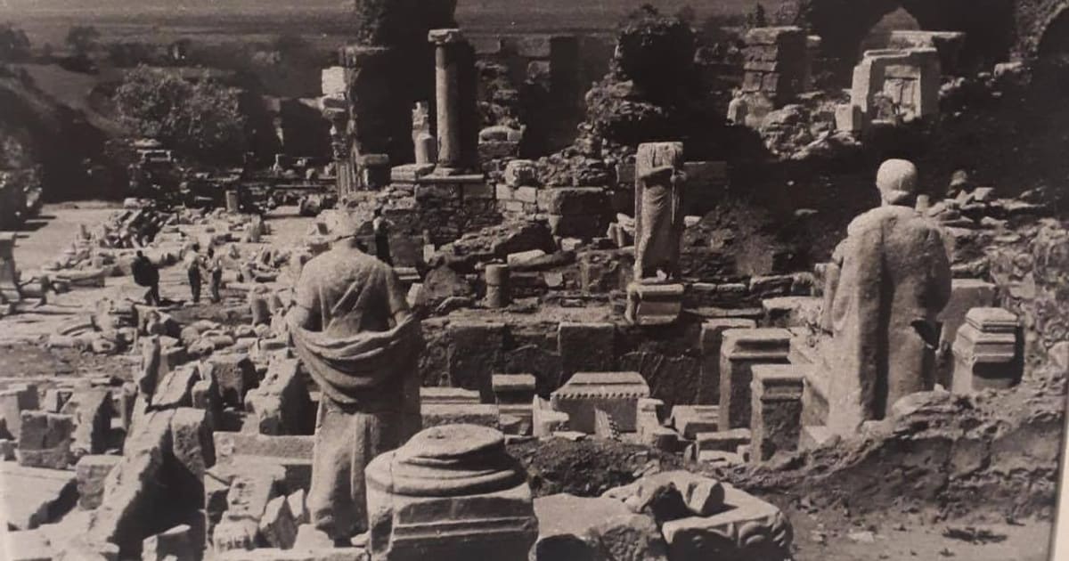An early excavation photograph of Ephesus — headless statues standing among fallen marble